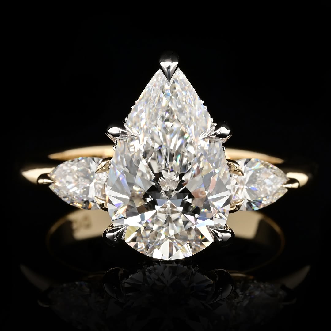 Top-down view of a 4 CT pear-cut lab-grown diamond engagement ring flanked by two smaller pear side diamonds on a high-polish yellow gold band