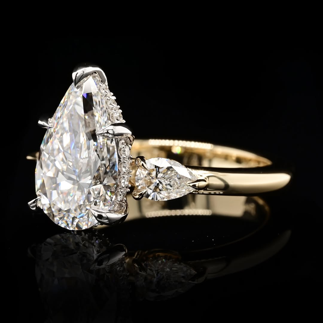 Side profile view of a 4 carat pear lab diamond ring showcasing the protective tip V-prong, white gold basket with hidden halo, and pear side stone setting.