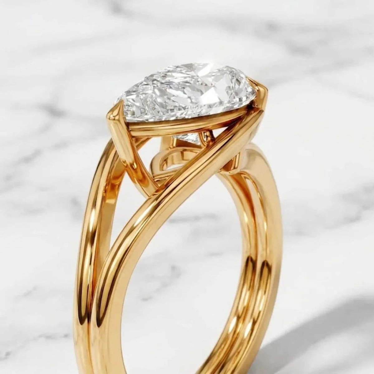 Close-up angled view of a 2 CT pear cut lab grown diamond set horizontally in a yellow gold bezel setting.