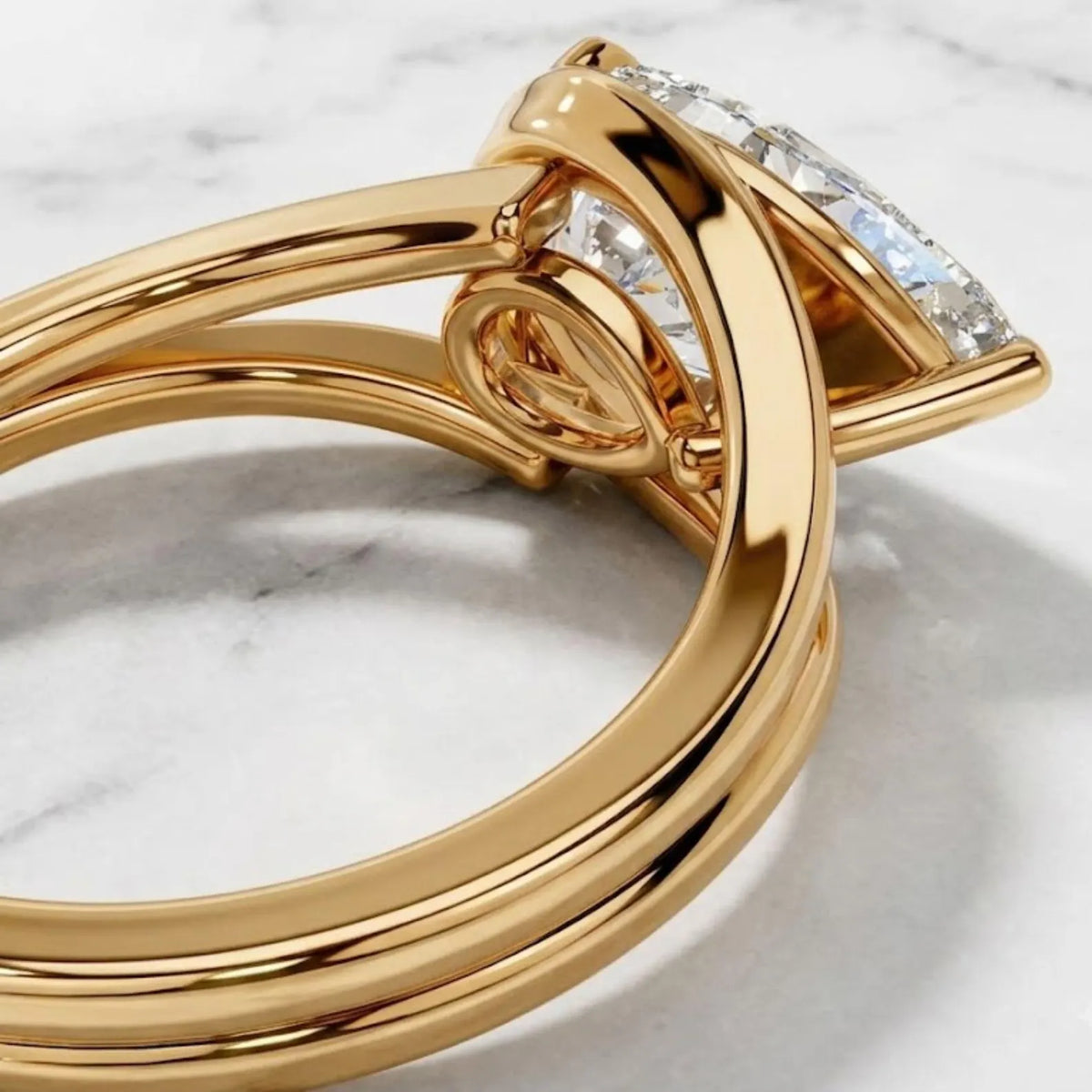 Close-up macro detail of the undergallery and split shank detailing on a gold bezel pear diamond ring.