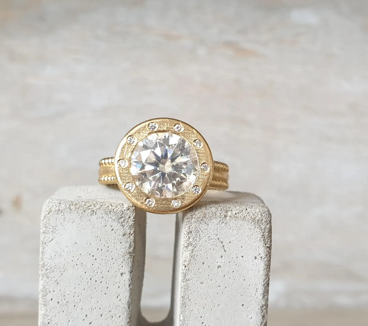 Front view of a 4 CT round lab grown diamond ring with brushed yellow gold halo bezel and flush diamond accents.