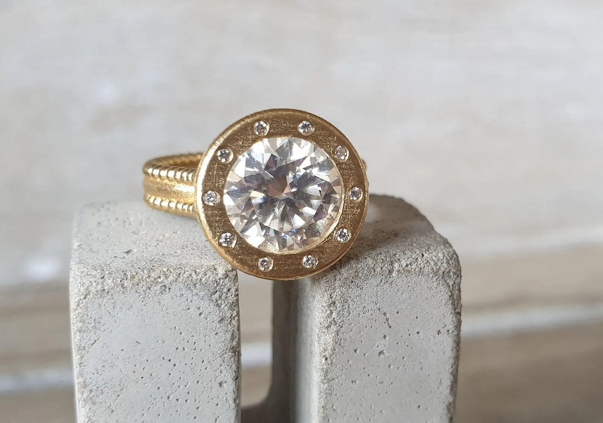 Detailed front view showcasing micro-accent diamonds flush set around the brushed gold bezel of a 4 CT round diamond ring.