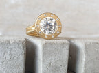 Close-up of 4 CT round lab grown diamond ring highlighting the matte gold bezel frame and beaded textured band.