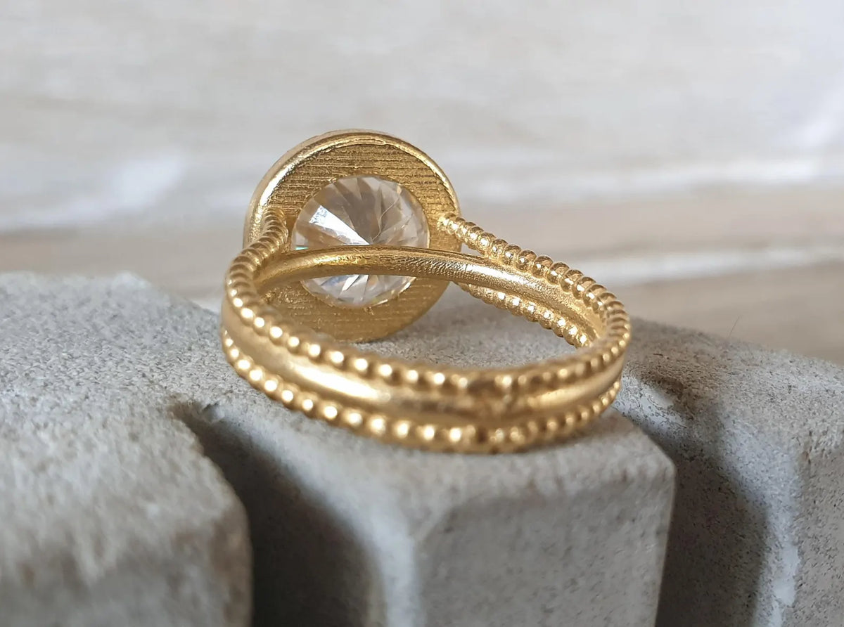 Back view showing the textured beaded double band and rear gallery opening of a yellow gold bezel ring.