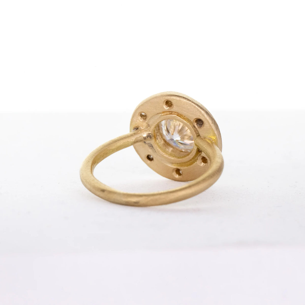 Underside view of a 4 CT round lab grown diamond ring showing the matte gold halo setting and smooth round band.