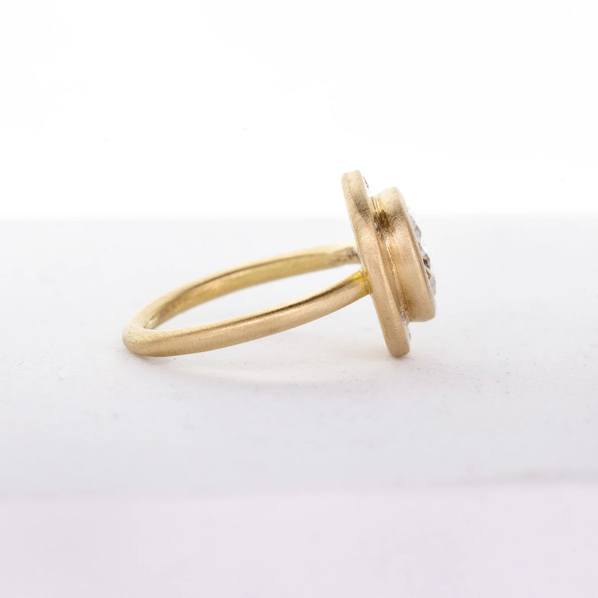 Side profile of a 14K yellow gold engagement ring featuring a tiered brushed bezel head and smooth shank.