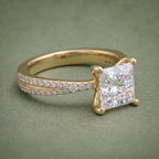 Close-up angled view highlighting the square 2 CT princess cut diamond and sparkling side pavé diamonds.