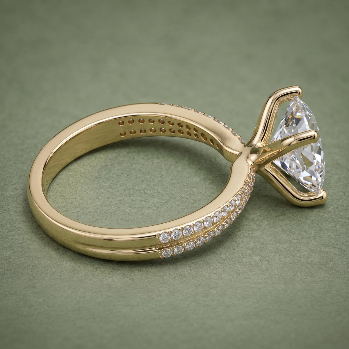 Side view showing the basket setting and double pavé band architecture of a gold princess cut ring.