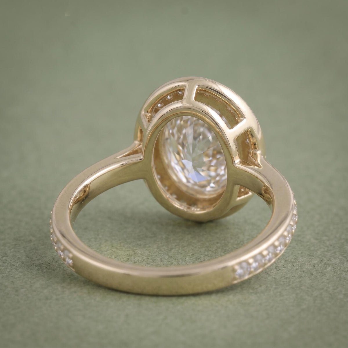 Inside shank and open lattice undergallery view of a yellow gold oval bezel halo diamond ring.