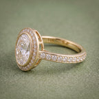 Side profile of a gold bezel halo ring showing the raised gallery construction and diamond pavé band.