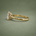 Side view displaying the open basket gallery and polished yellow gold shank of a cushion cut diamond ring.