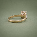 Three-quarter rear angle of a simple gold solitaire engagement ring with an elongated cushion center diamond.