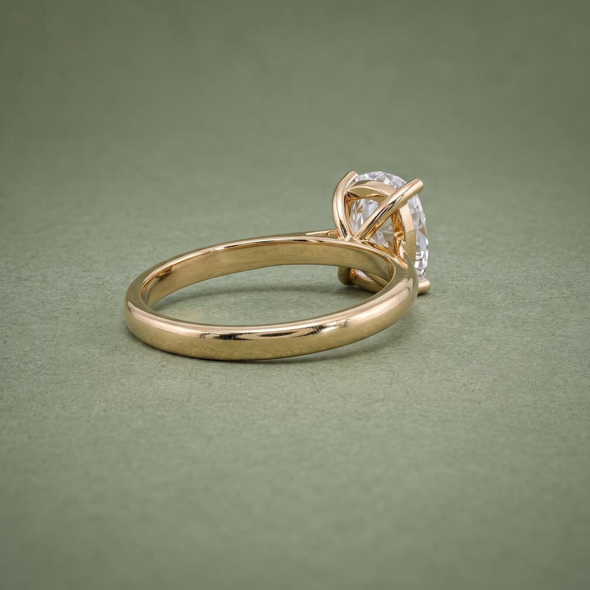 Three-quarter rear angle of a simple gold solitaire engagement ring with an elongated cushion center diamond.