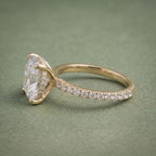 Side profile view of a yellow gold cushion cut diamond ring displaying the hidden halo and pavé shank.