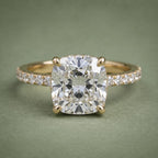 Direct front top-down view of a 3 CT cushion cut lab diamond set on a yellow gold pavé accent band.