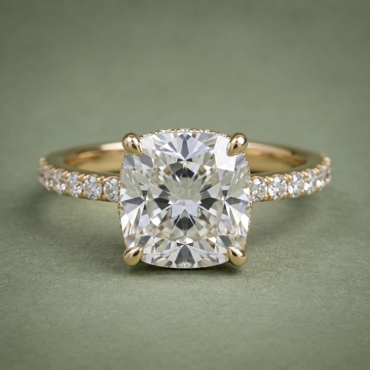 Direct front top-down view of a 3 CT cushion cut lab diamond set on a yellow gold pavé accent band.