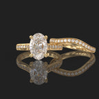 Side-by-side perspective of a 3 carat oval diamond solitaire ring and matching curved pavé wedding ring.