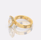 A yellow gold ring with pear -cut clear gemstone, displayed on a reflective light gray surface.