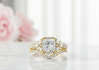 3 CT princess cut lab diamond engagement ring with floral cluster accents and curved chevron band on marble surface.