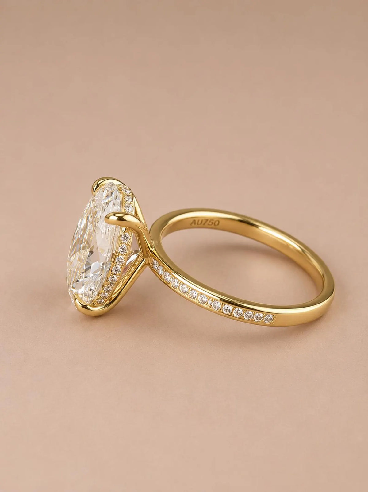 Angled view of a 4 carat oval lab diamond engagement ring with pavé band and AU750 gold stamp.