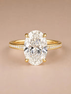 Direct front view of a 4 CT oval cut lab grown diamond with claw prongs on a yellow gold pavé band.