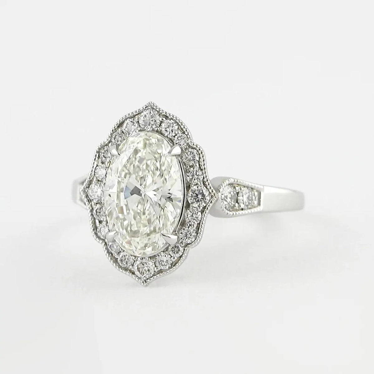 High-angle view of a 3 carat oval lab grown diamond engagement ring with a scalloped milgrain halo.