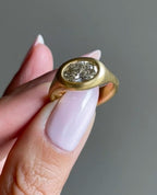 Close-up of a horizontal bezel-set oval lab diamond with a satin brushed gold band.