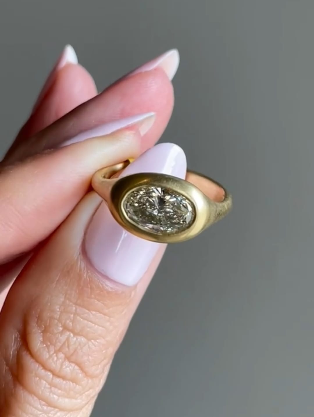 Front angle of a 2 CT oval cut lab grown diamond in a thick yellow gold bezel frame.