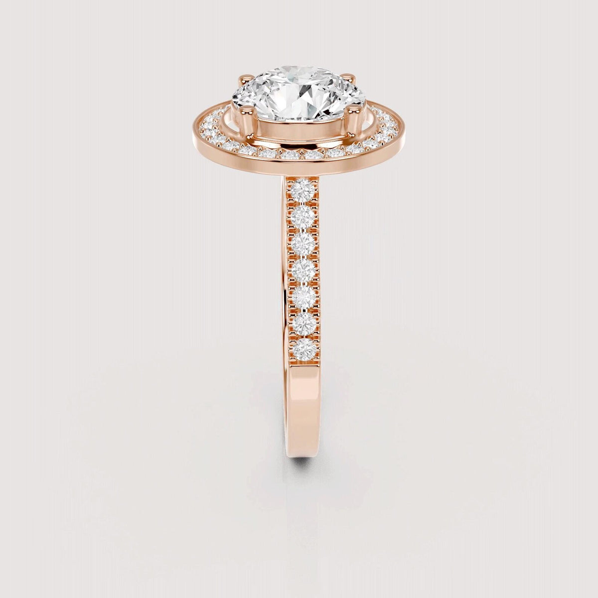 A rose gold ring with a large oval-cut center stone and a halo of small clear stones, featuring a shank paved with round stones, shown on a light gray background.