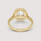 A yellow gold ring with a large round clear center stone and a halo of small clear stones, shown on a light gray background.