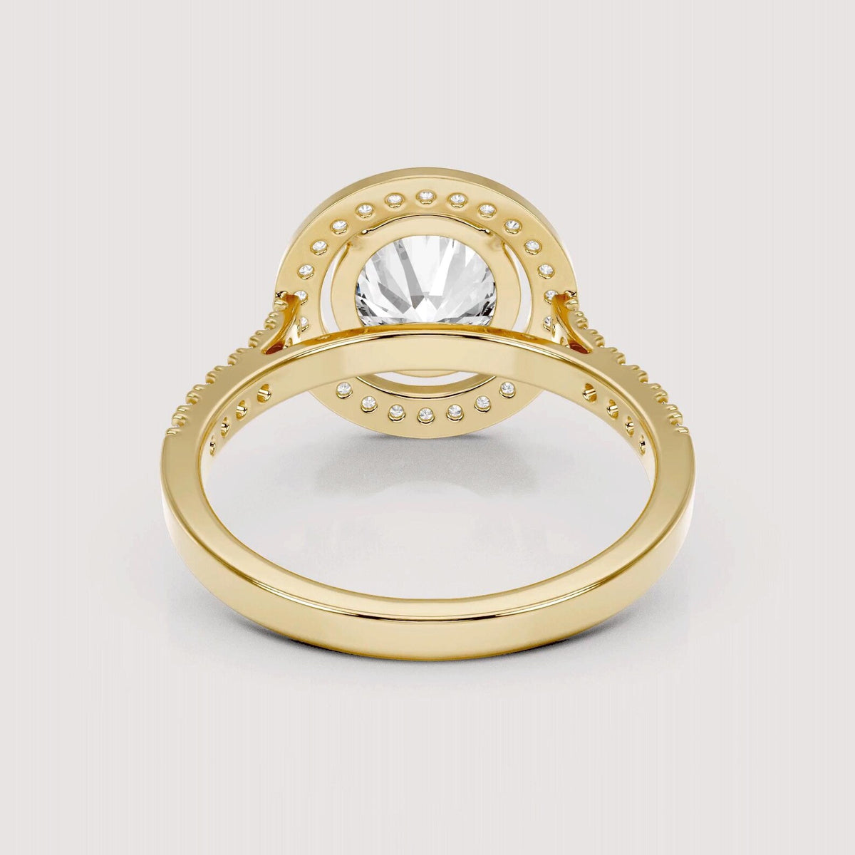 A yellow gold ring with a large round clear center stone and a halo of small clear stones, shown on a light gray background.