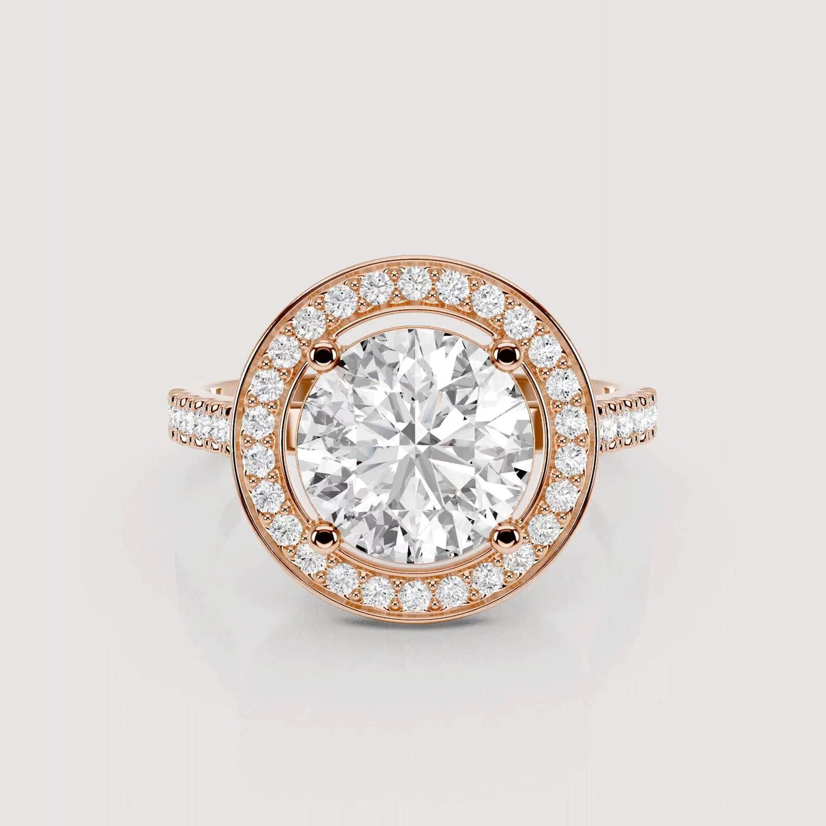 A rose gold halo ring featuring a large round-cut center stone surrounded by a double halo of smaller round stones, with a split shank band also accented with small stones, shown on a light gray background.