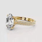 Gold ring with a large diamond and smaller diamonds on the band against a light gray background
