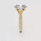 A yellow gold solitaire engagement ring featuring a large round brilliant-cut diamond center stone and a pavé diamond shank, shown on a light gray background.