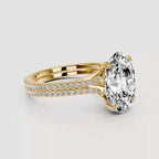 Gold ring with a large diamond and smaller diamonds on the band against a light gray background