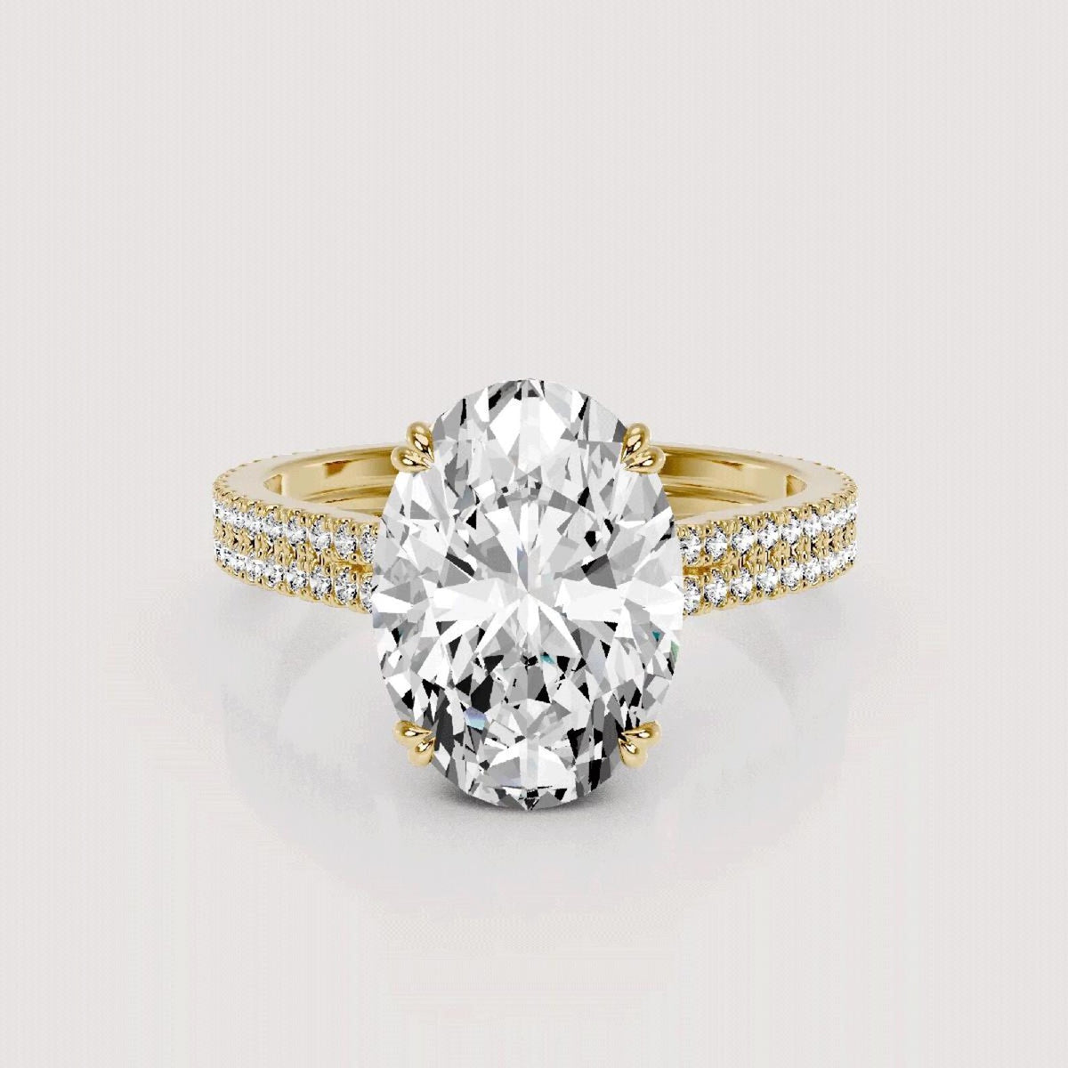 An oval-cut diamond engagement ring with a yellow gold band accented by pavé diamonds, shown on a light gray background.
