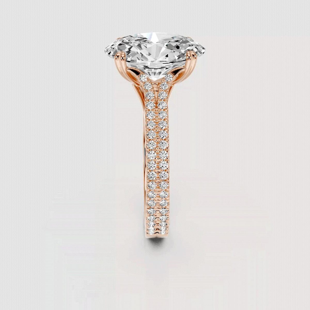 A rose gold solitaire engagement ring featuring a large round brilliant-cut diamond center stone and a pavé-set diamond shank, shown on a light gray background.