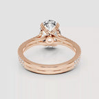 Rose gold ring with a large round clear gemstone in a prong setting, featuring an intertwined band design with small pavé accents and a central pearl-like accent, shown on a light gray background.