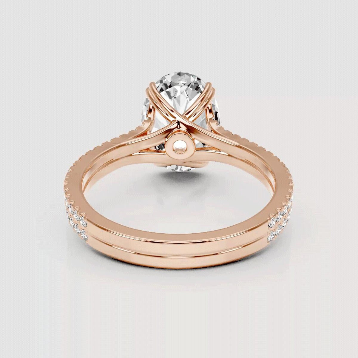 Rose gold ring with a large round clear gemstone in a prong setting, featuring an intertwined band design with small pavé accents and a central pearl-like accent, shown on a light gray background.