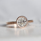 Front view of a 2 CT round lab grown diamond engagement ring in a rose gold milgrain bezel setting with a braided textured band.