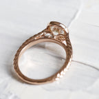 Side profile view showing delicate scrollwork filigree under the bezel setting and braided rose gold band of a 2 carat lab grown diamond ring.