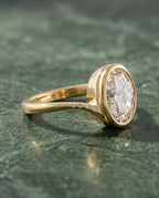 Three-quarter side angle showing full bezel profile and flush-set accent diamonds along the curved yellow gold shoulder of 3 Carat Oval Ring