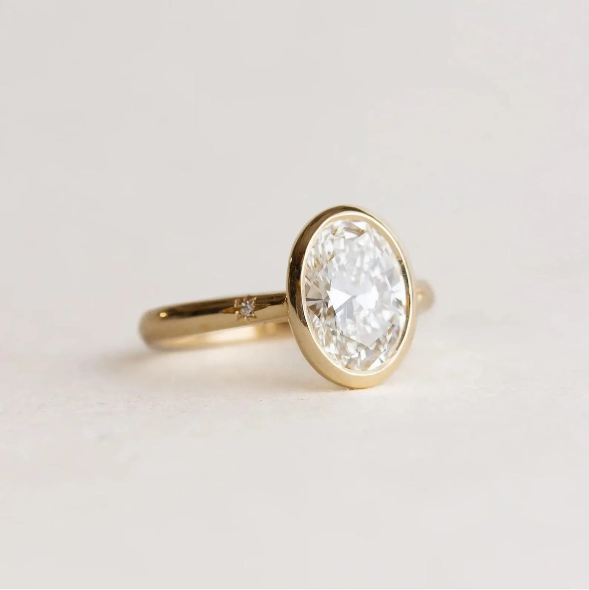 Direct side profile view of 2 Carat Oval Cut Lab Grown Diamond Bezel Engagement Ring showing open gallery struts and gold band