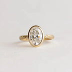 Top-down view of 2 Carat Oval Cut Lab Grown Diamond Bezel Ring in yellow gold with celestial star-set accent diamonds