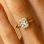 On-finger view of 3 Carat Emerald Cut Lab Grown Diamond Bezel Ring in yellow gold with hand-engraved details