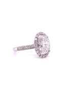 Side angle view of a 4 CT oval cut lab grown diamond engagement ring with a halo setting and multi-row pave band in white gold.
