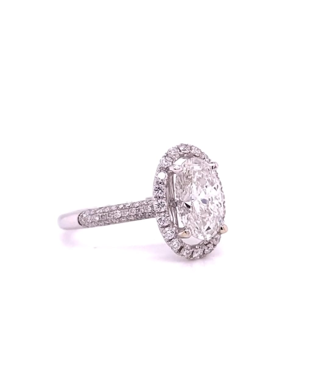 Side angle view of a 4 CT oval cut lab grown diamond engagement ring with a halo setting and multi-row pave band in white gold.