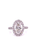 Top-down view of a 4 carat oval lab created diamond ring surrounded by a round diamond halo on a pave-encrusted band.