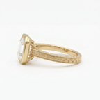 Side view of a 3 carat Asscher cut lab grown diamond engagement ring in yellow gold featuring an engraved leaf pattern band and bezel frame.