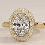 An oval halo ring featuring a large oval-cut center stone surrounded by double rows of small pavé-set diamonds, set in yellow gold on a matching band, shown against a neutral light beige background.